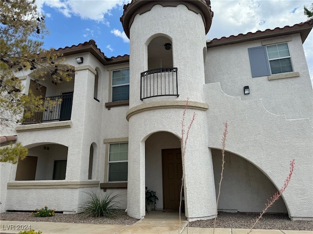 view of front of property with a tile roof, a balcony, and stucco siding