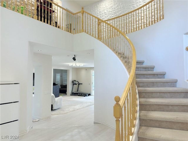 staircase featuring a towering ceiling and baseboards