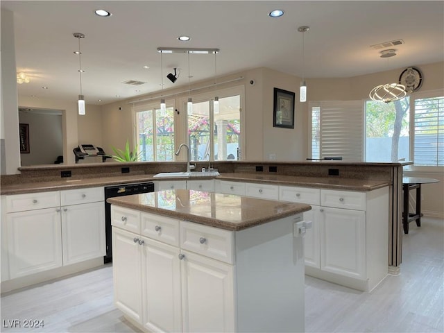 kitchen with recessed lighting, a sink, a kitchen island, dark stone counters, and dishwashing machine