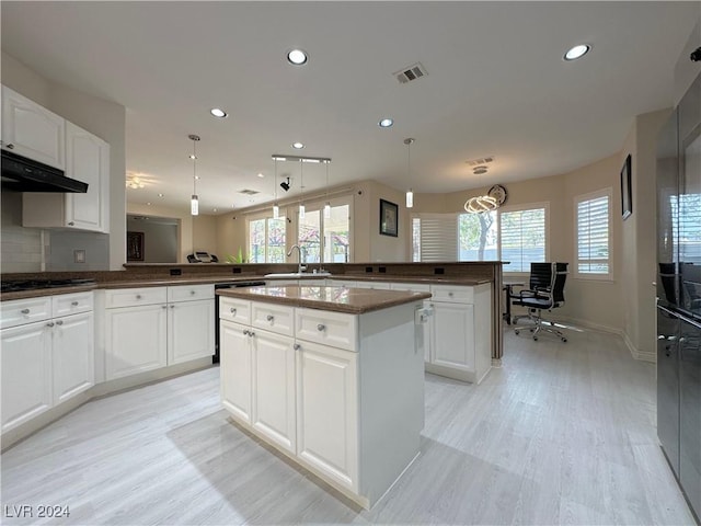 kitchen featuring a peninsula, light wood finished floors, visible vents, and white cabinets