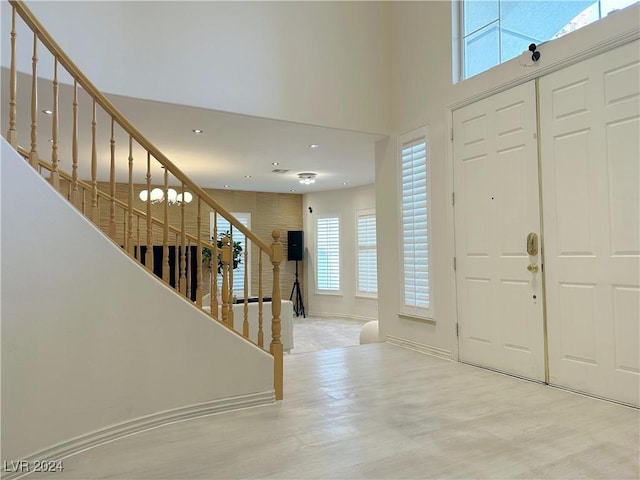 foyer entrance featuring baseboards, stairway, a high ceiling, and wood finished floors