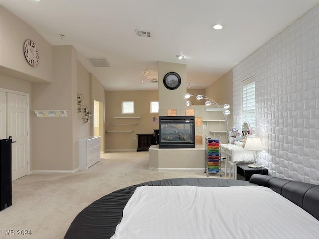 bedroom with light carpet, a multi sided fireplace, visible vents, and baseboards