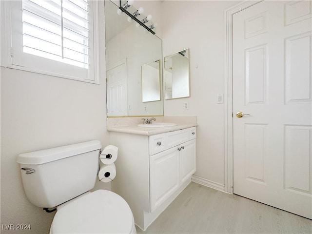 bathroom featuring toilet, wood finished floors, and vanity