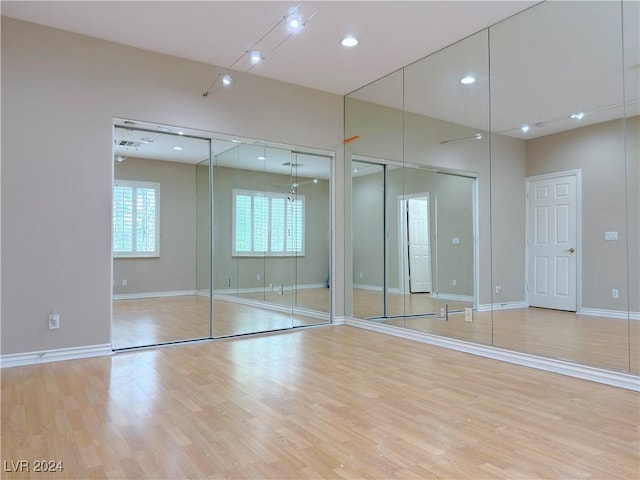 unfurnished bedroom with baseboards, recessed lighting, light wood-style flooring, and multiple closets