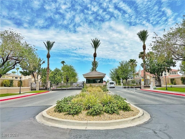 view of road featuring sidewalks, a gated entry, and curbs