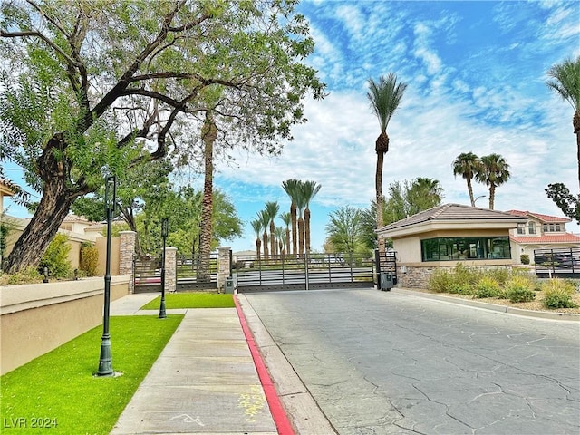 view of road featuring curbs, a gated entry, sidewalks, and a gate