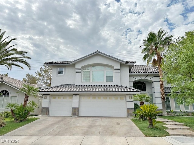 view of front of house featuring driveway, an attached garage, a tile roof, and stucco siding