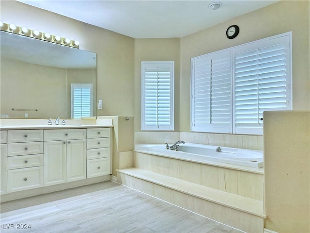 full bathroom with vanity, a bath, and wood finished floors