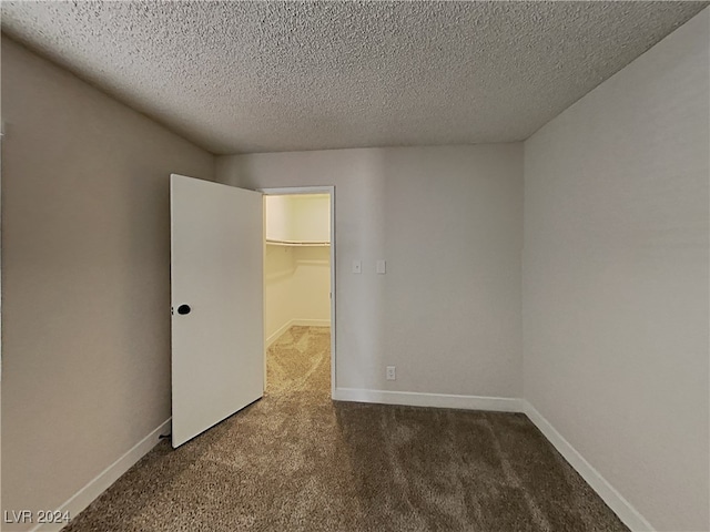 unfurnished room with a textured ceiling and carpet floors