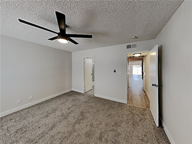 unfurnished bedroom featuring ceiling fan, a textured ceiling, and light carpet