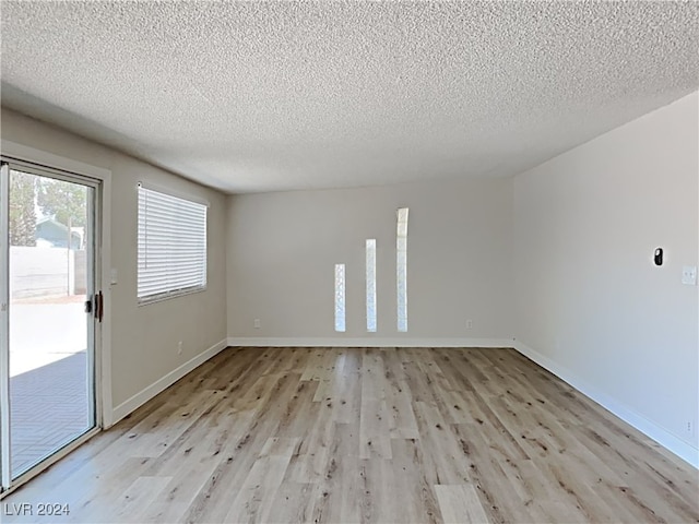 spare room featuring light hardwood / wood-style flooring and a textured ceiling