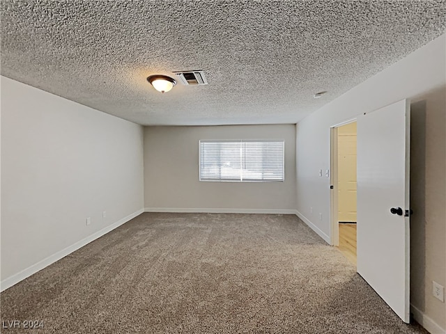 unfurnished room featuring a textured ceiling and carpet