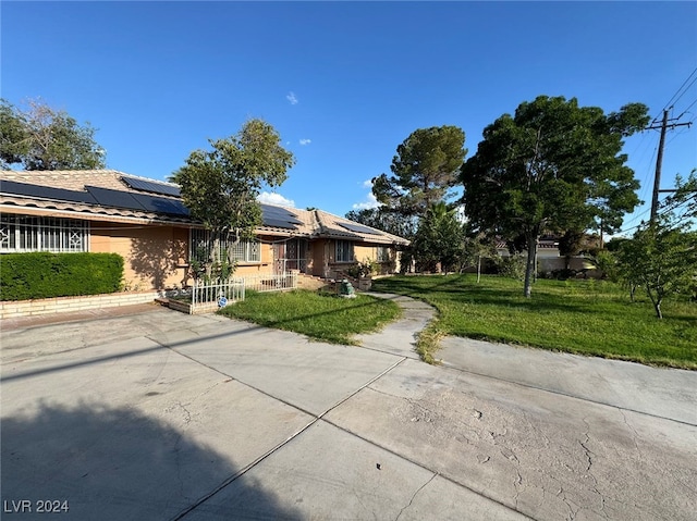 view of front of house with a front yard and solar panels