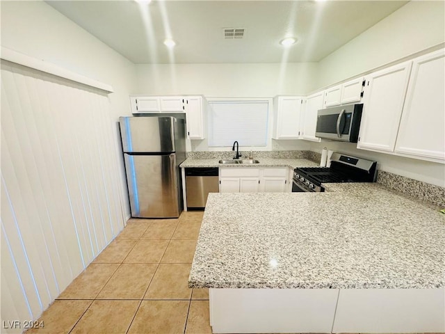 kitchen featuring light tile patterned floors, appliances with stainless steel finishes, light stone countertops, white cabinets, and sink