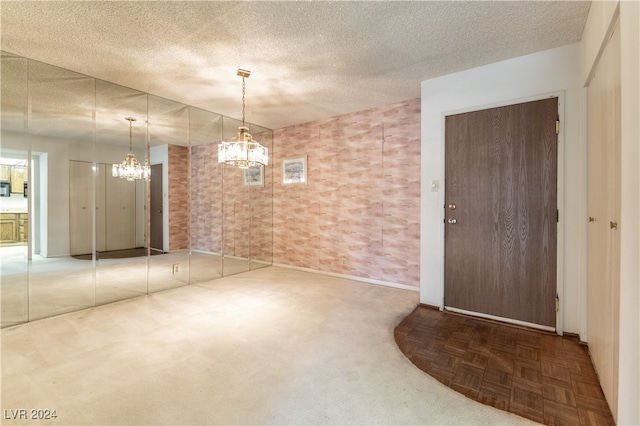 unfurnished room featuring a notable chandelier, a textured ceiling, and parquet flooring