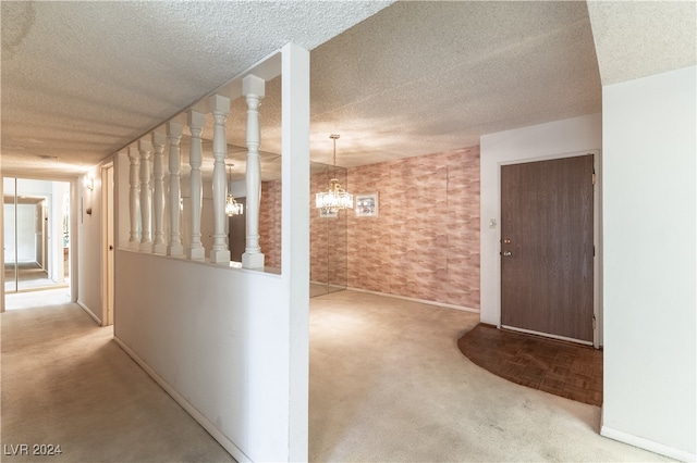 corridor featuring a textured ceiling, light colored carpet, and an inviting chandelier