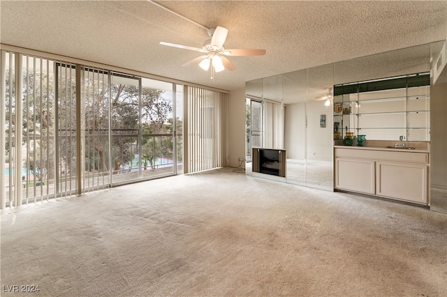 unfurnished living room with light carpet, a textured ceiling, and ceiling fan