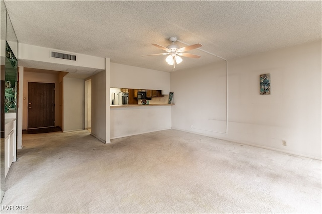 unfurnished living room with ceiling fan, a textured ceiling, and light carpet