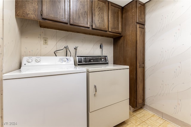 clothes washing area with washing machine and clothes dryer, light tile patterned floors, and cabinets