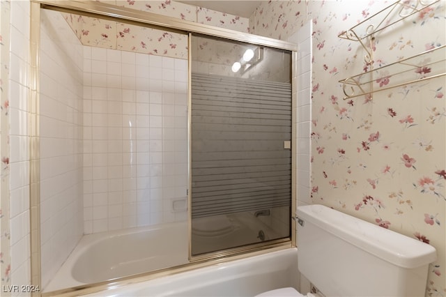 bathroom with toilet and shower / bath combination with glass door