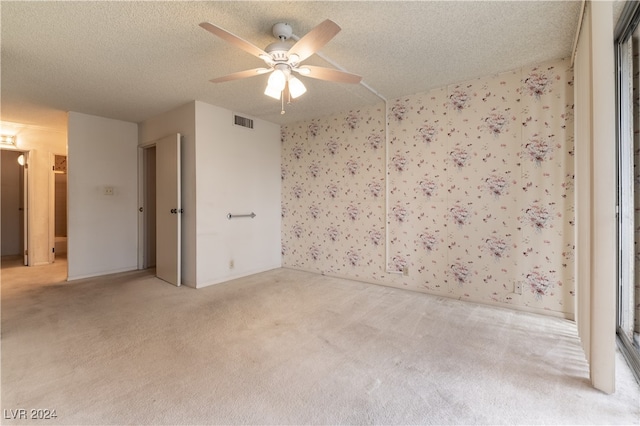 carpeted spare room with a textured ceiling and ceiling fan