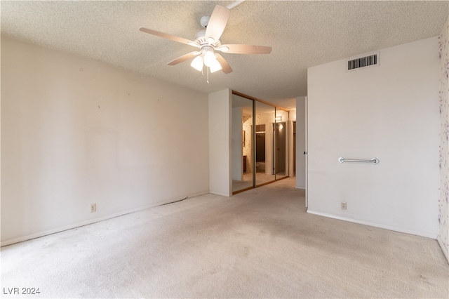 unfurnished bedroom featuring ceiling fan, a textured ceiling, light carpet, and a closet