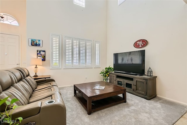 living room with a towering ceiling and light carpet