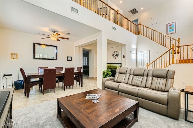 living room with ceiling fan, a towering ceiling, and light tile patterned floors