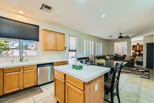 kitchen with stainless steel dishwasher, a kitchen island, sink, and tile countertops