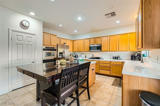 kitchen featuring light tile patterned flooring, stainless steel appliances, sink, and a center island