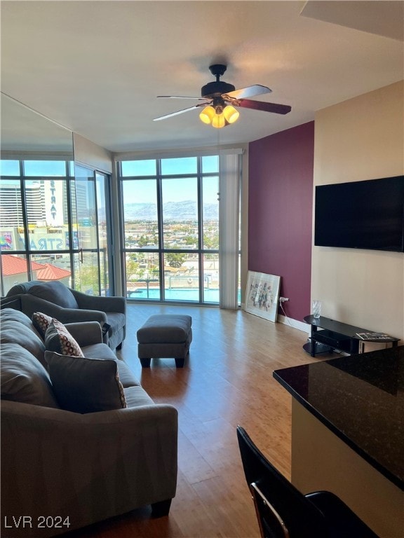 living room featuring ceiling fan, hardwood / wood-style floors, and a wall of windows