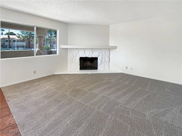 unfurnished living room featuring a textured ceiling, carpet flooring, and a fireplace