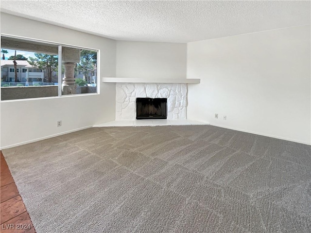 unfurnished living room featuring carpet flooring, a textured ceiling, and a fireplace