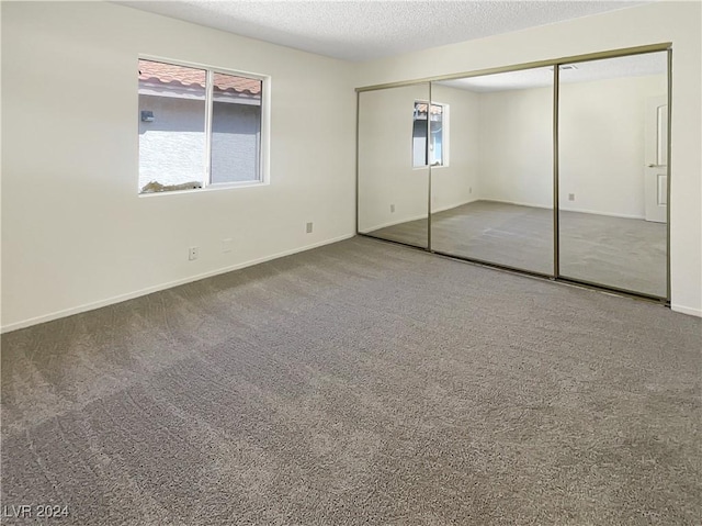 unfurnished bedroom featuring carpet flooring, a textured ceiling, and a closet