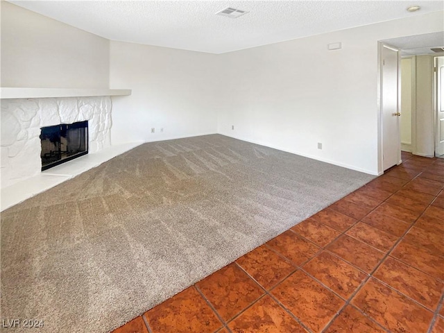 unfurnished living room with carpet floors, a textured ceiling, and a fireplace