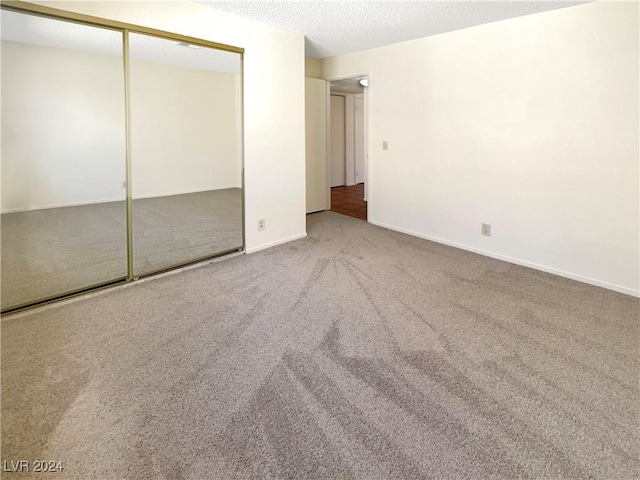 unfurnished bedroom featuring a closet, a textured ceiling, and carpet