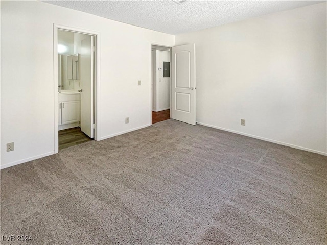 unfurnished bedroom with connected bathroom, electric panel, a textured ceiling, and carpet flooring