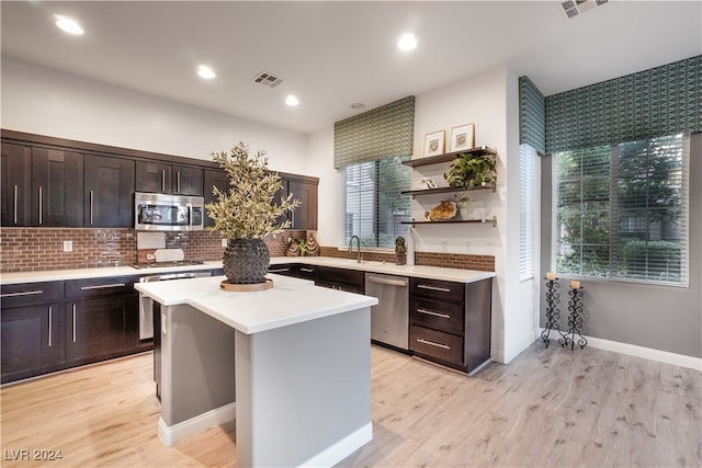 kitchen with decorative backsplash, light hardwood / wood-style flooring, dark brown cabinetry, a center island, and stainless steel appliances