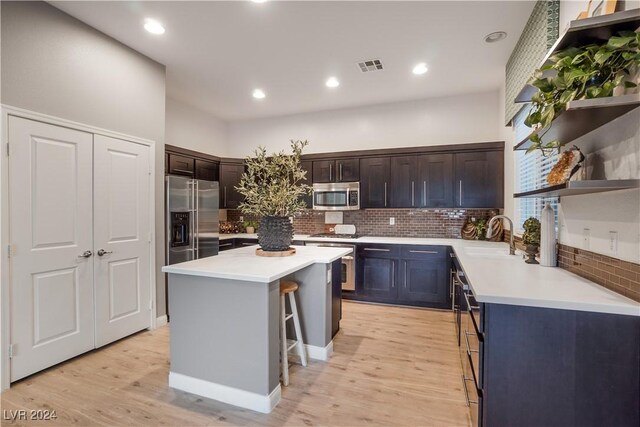 kitchen with sink, light wood-type flooring, appliances with stainless steel finishes, and decorative backsplash