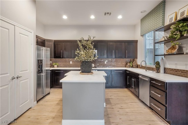 kitchen featuring visible vents, appliances with stainless steel finishes, a center island, light countertops, and a sink