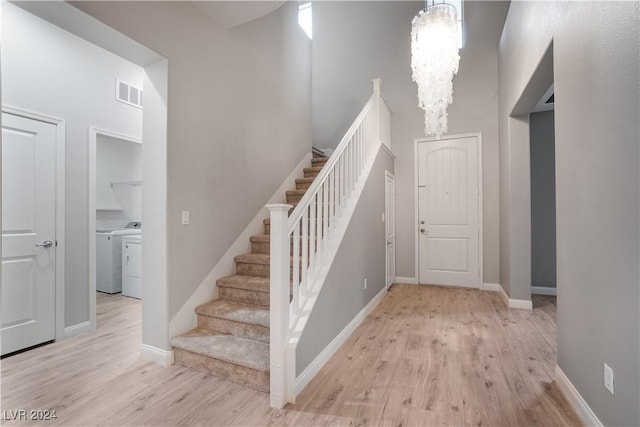 stairway featuring an inviting chandelier, visible vents, wood finished floors, and washing machine and clothes dryer