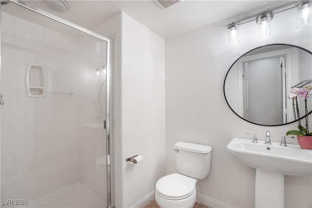 bathroom with toilet, a sink, visible vents, baseboards, and a stall shower