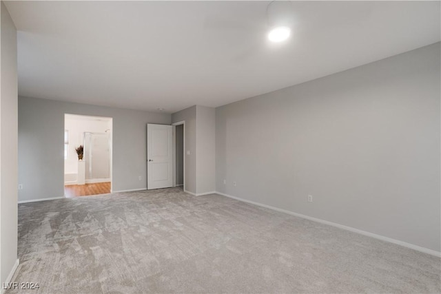 unfurnished bedroom with baseboards, connected bathroom, and light colored carpet