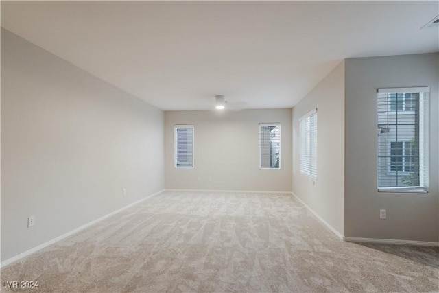 spare room with baseboards and light colored carpet