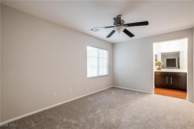 unfurnished room featuring ceiling fan, light colored carpet, a sink, visible vents, and baseboards