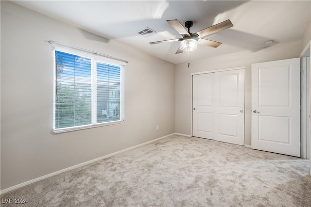 unfurnished bedroom featuring a closet, visible vents, a ceiling fan, light carpet, and baseboards