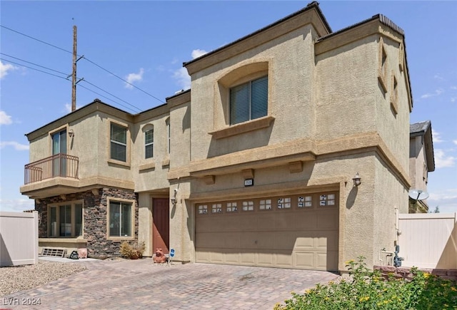 view of front of house with stucco siding, fence, a balcony, and a garage