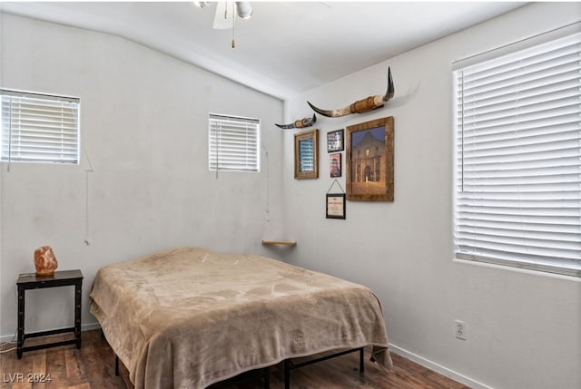 bedroom featuring ceiling fan, vaulted ceiling, dark wood-type flooring, and multiple windows