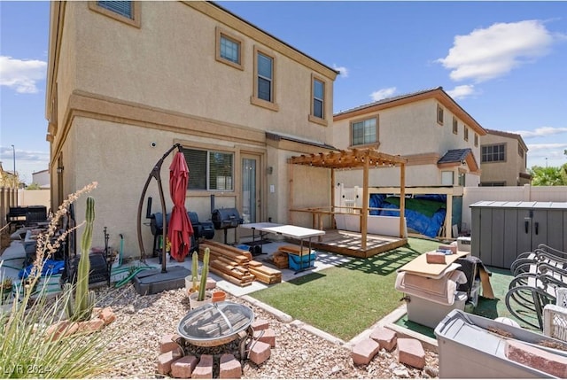 back of house featuring fence, a pergola, stucco siding, a wooden deck, and a fire pit