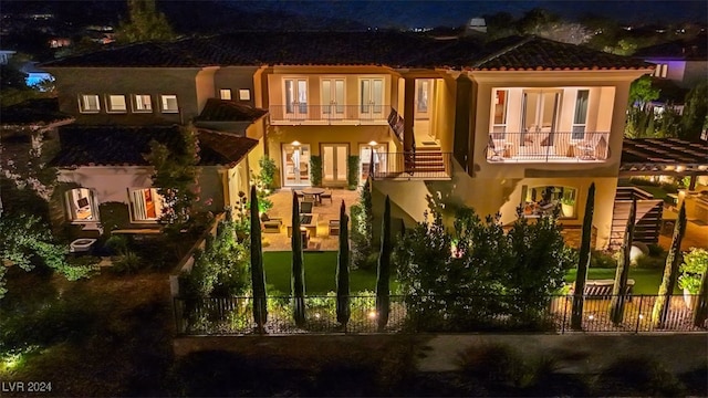 back house at twilight featuring a balcony